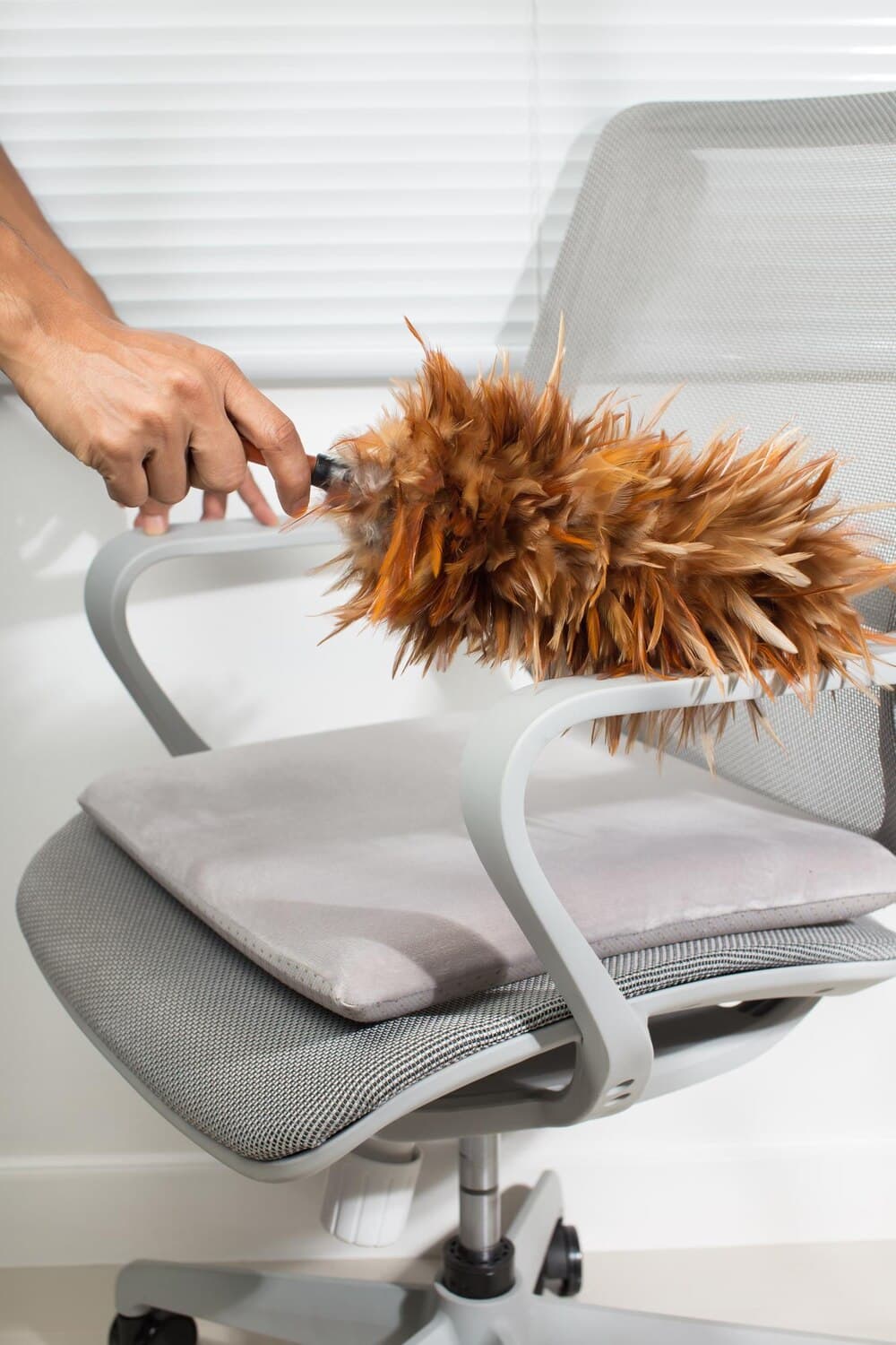 Feather duster being used on a cushioned chair
