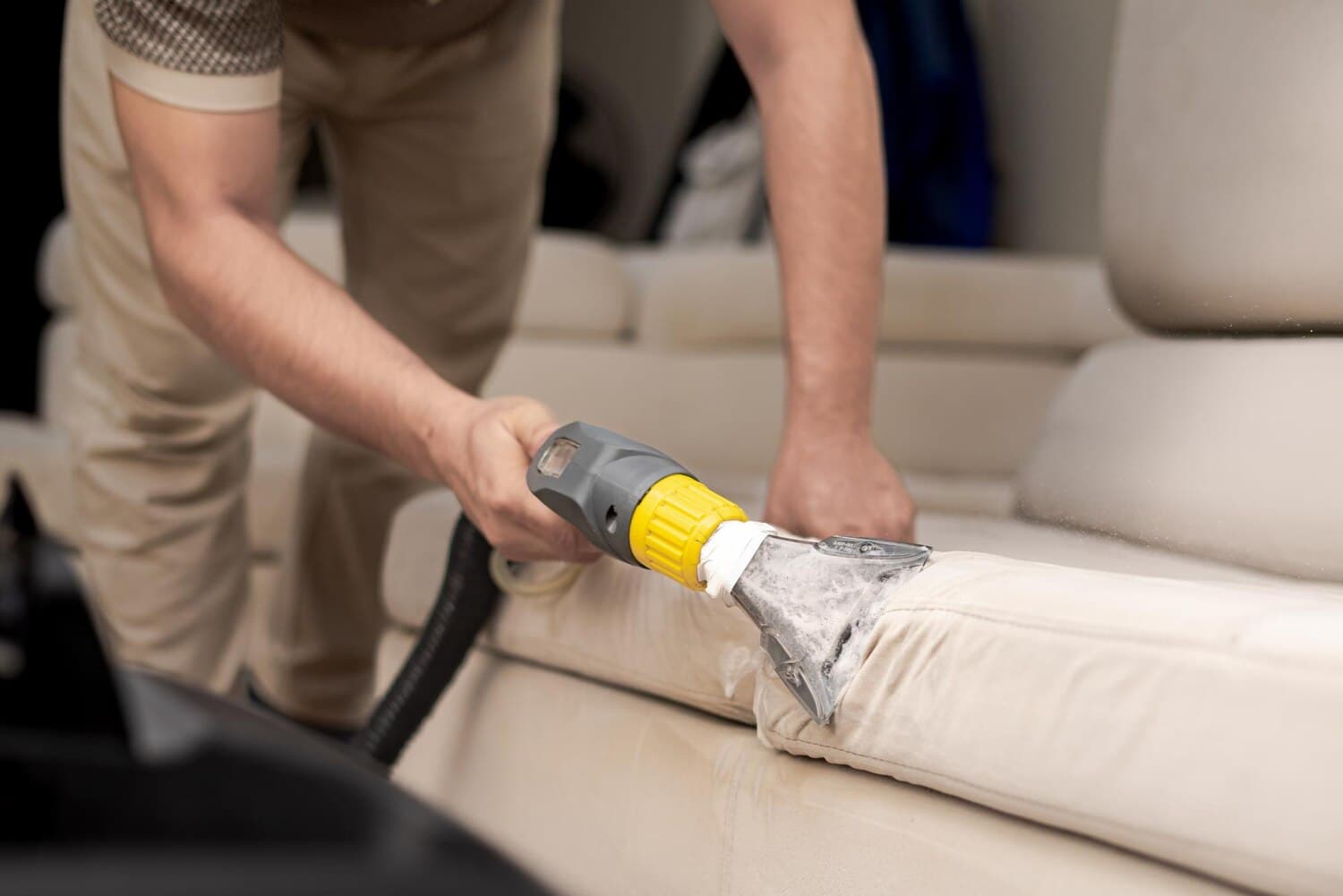 Upholstery cleaning machine lifting dirt from a cream sofa