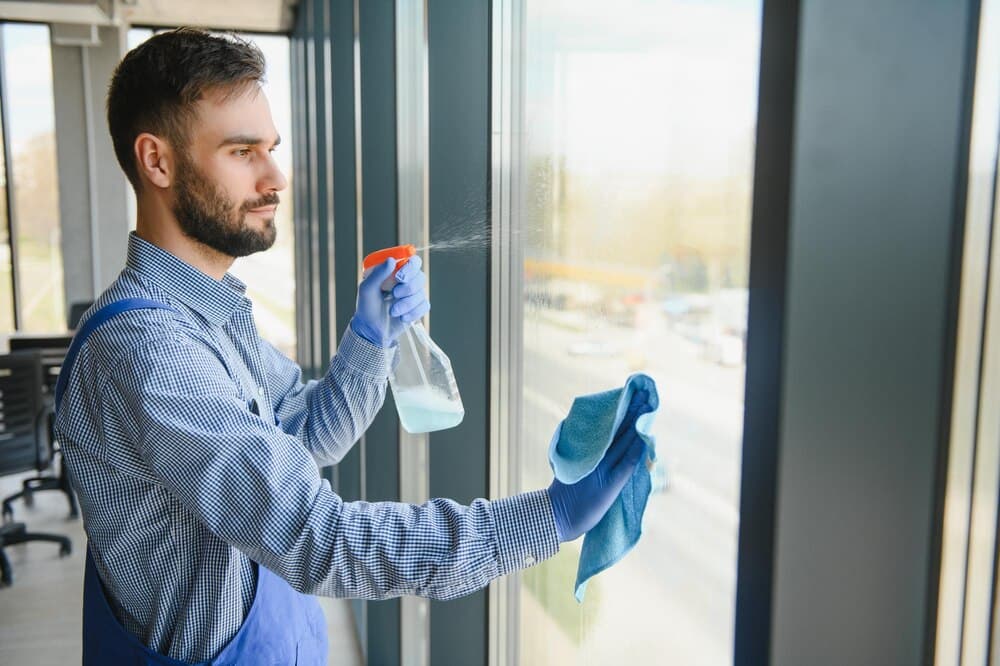 Cleaner spraying and wiping a large window