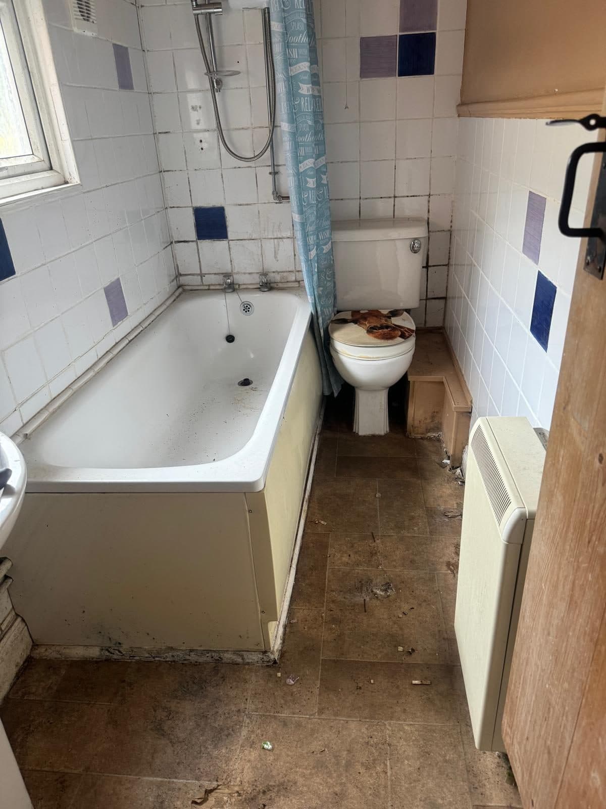 Bathroom before cleaning: marked bath panel, grimy floor and debris